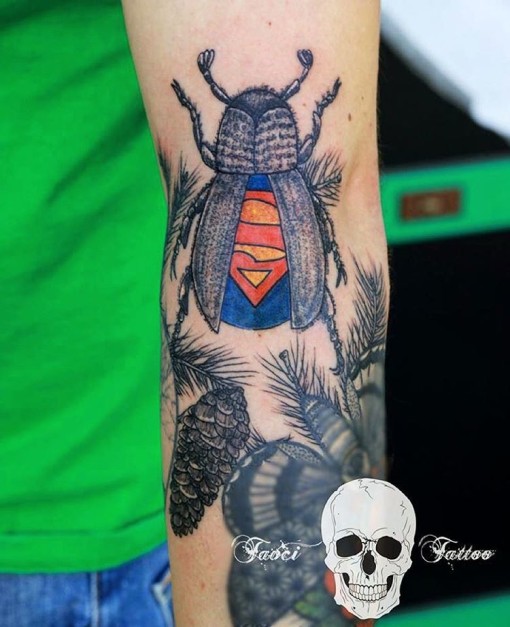 A tattoo of a bug with a superman mark on its back
