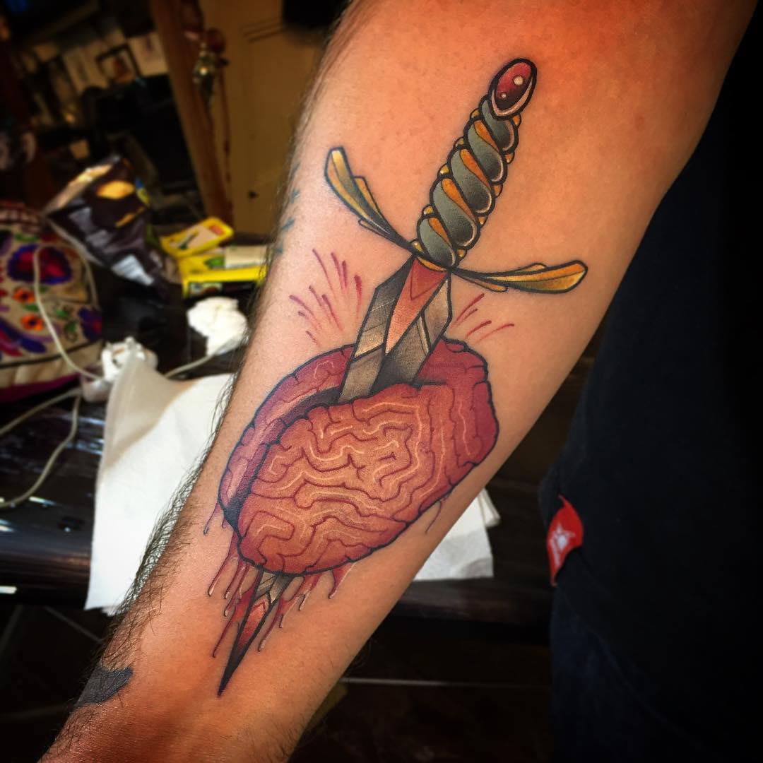 neo-traditional tattoo on arm of dagger and brain