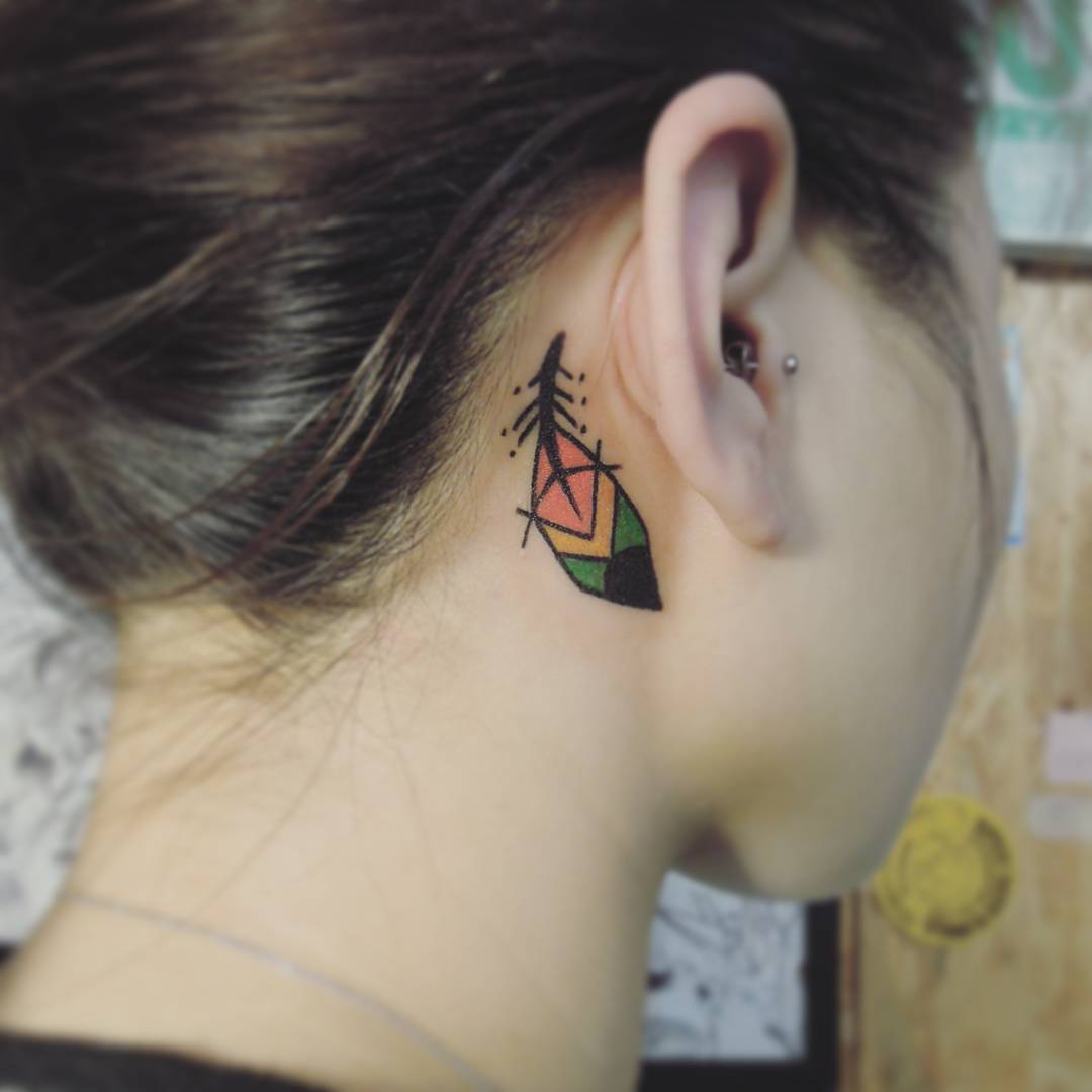 small colorful feather tattoo which looks like something Indian placed behind girl's ear