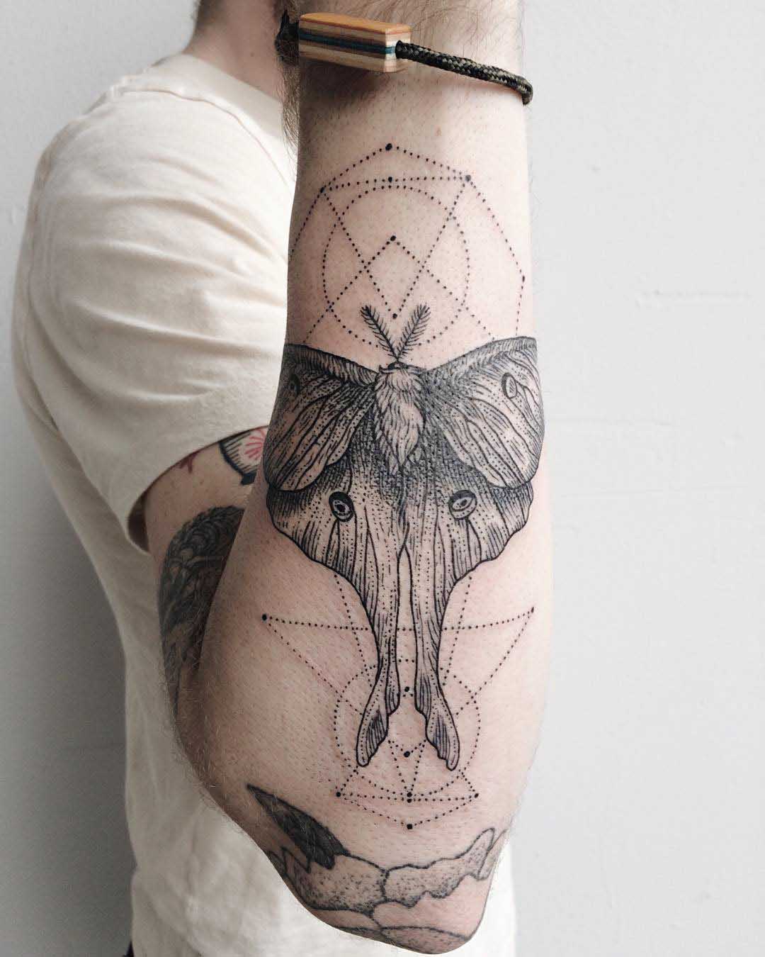 forearm tattoo of a moth and dots geometry