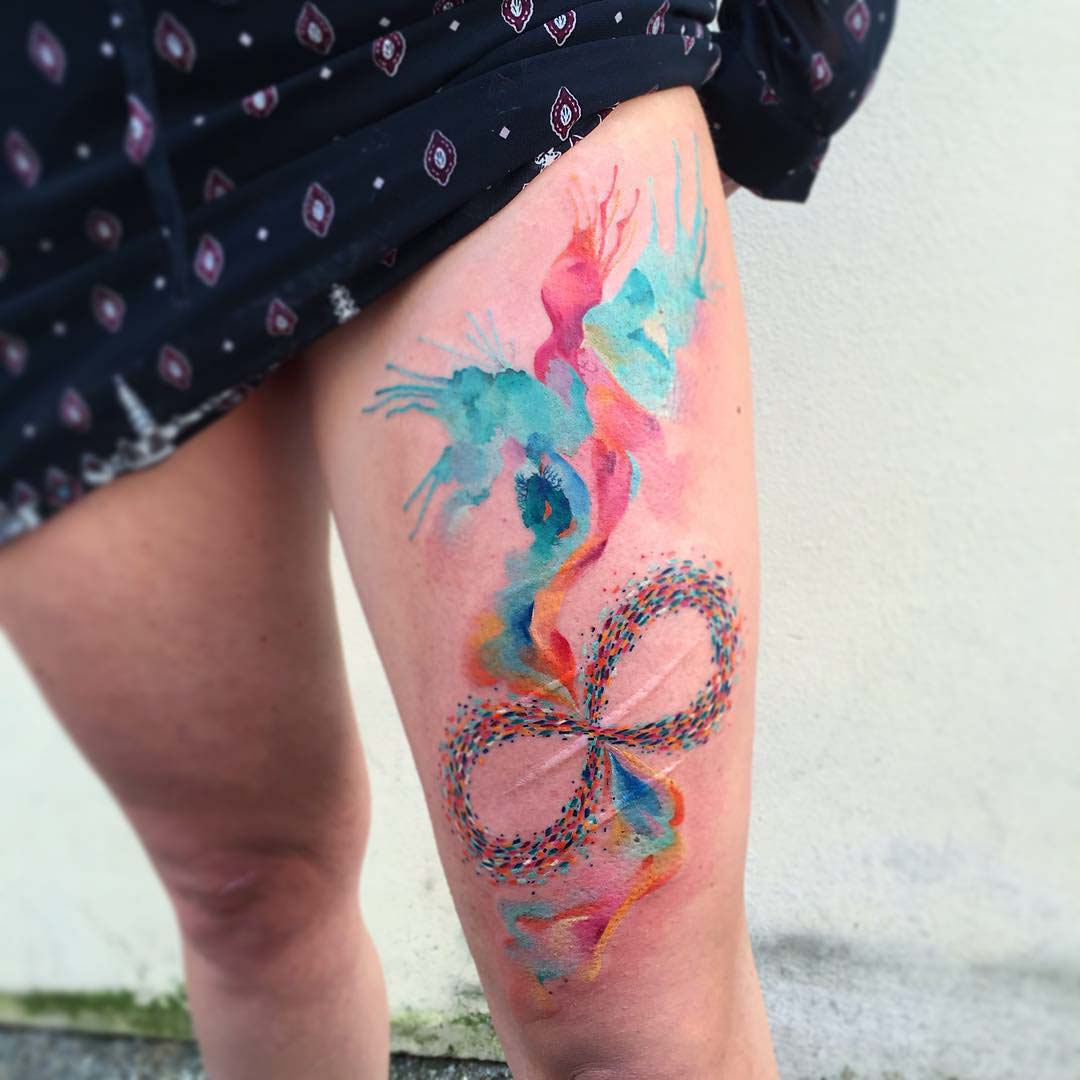 bright watercolor tattoo on thigh