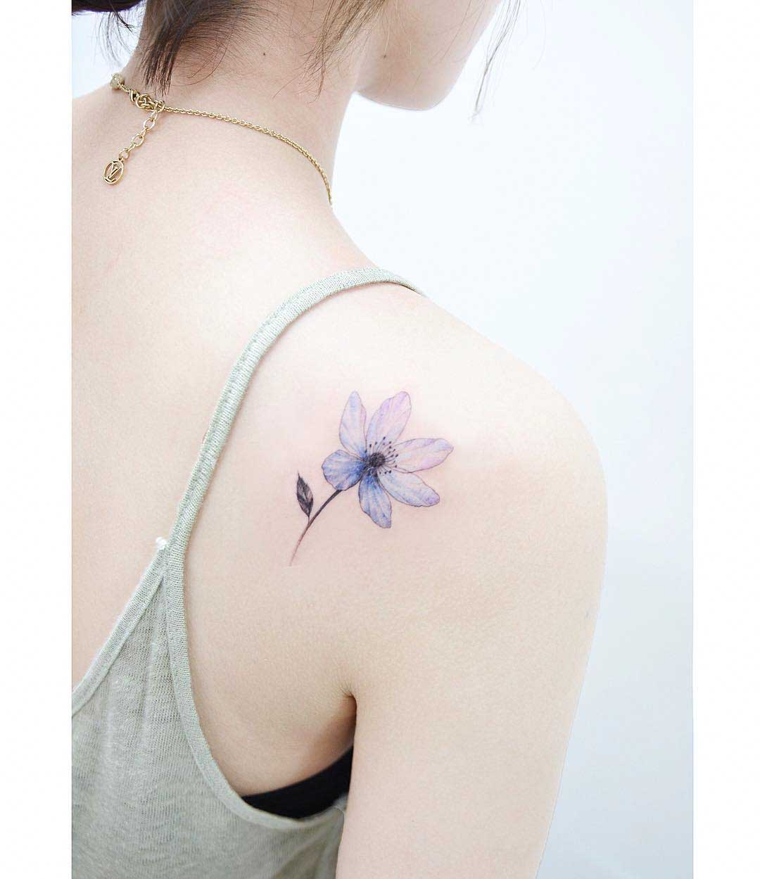 flower bluish tattoo on back of shoulder