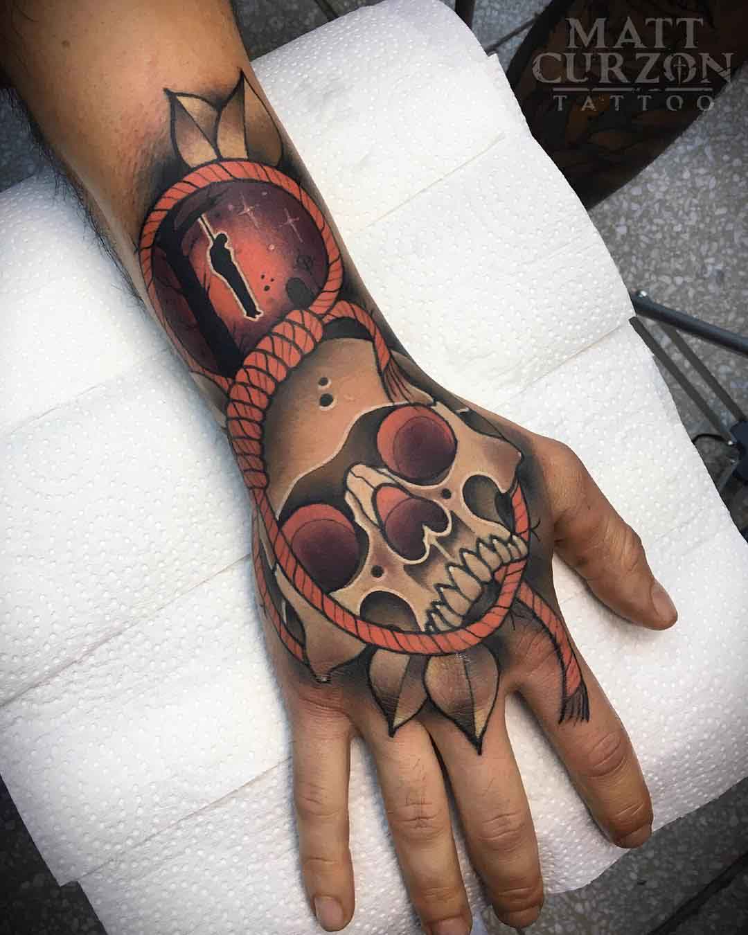 skull tattoo on hand with rope and hanged man
