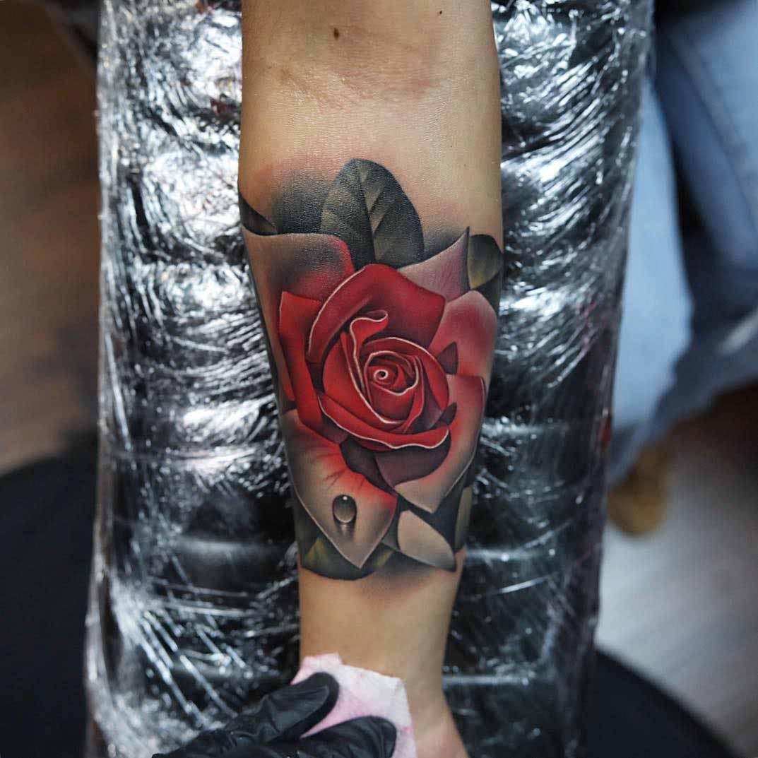 Black and grey shaded small rose tattoo above heel